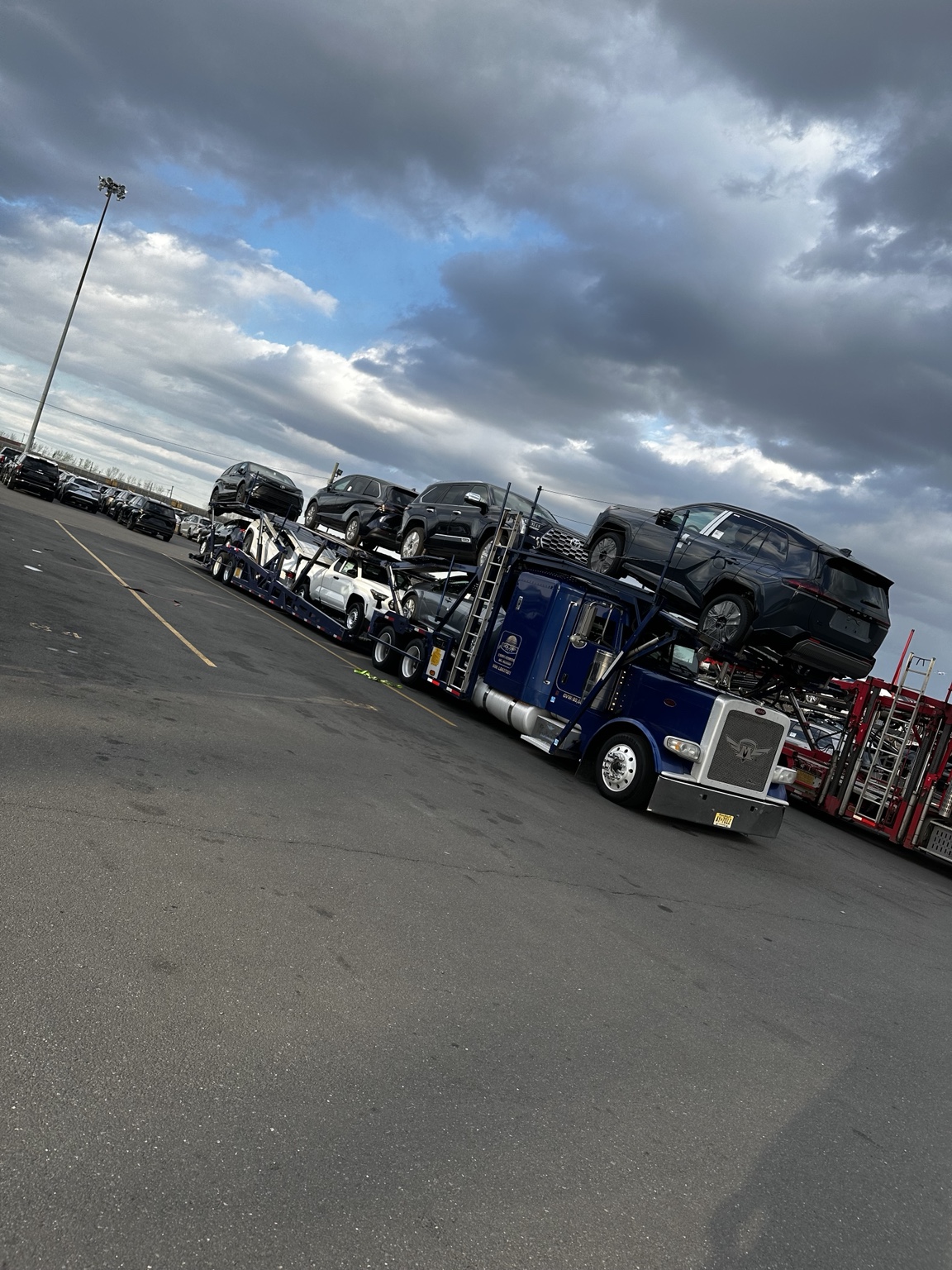 Blue Golden Auto Transport carrier under dramatic sky